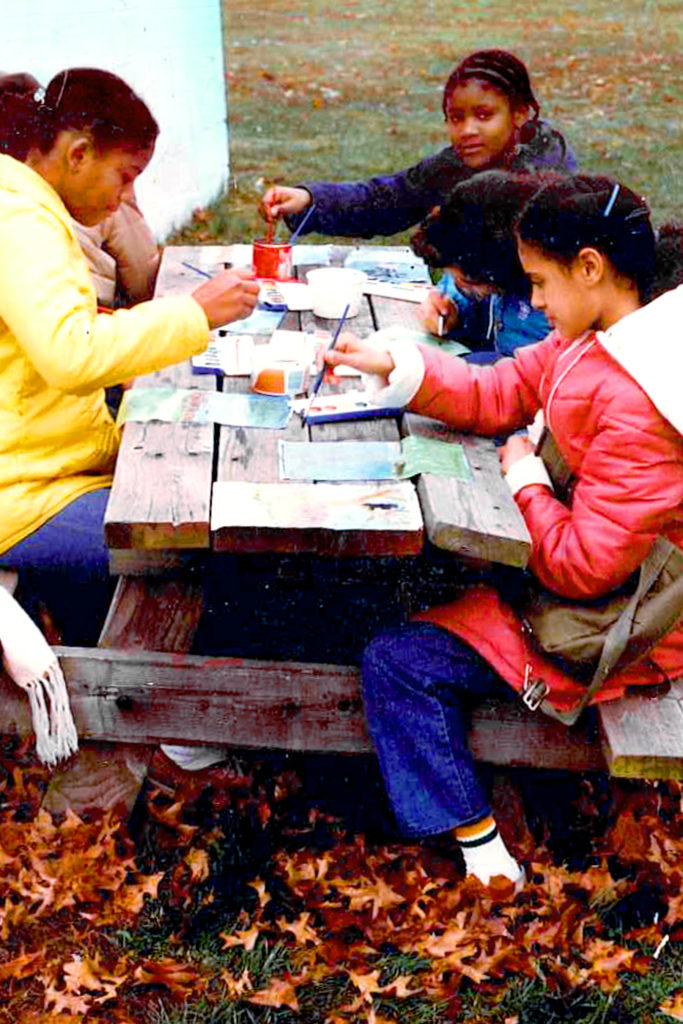 Children sitting outside at picnic table drawing